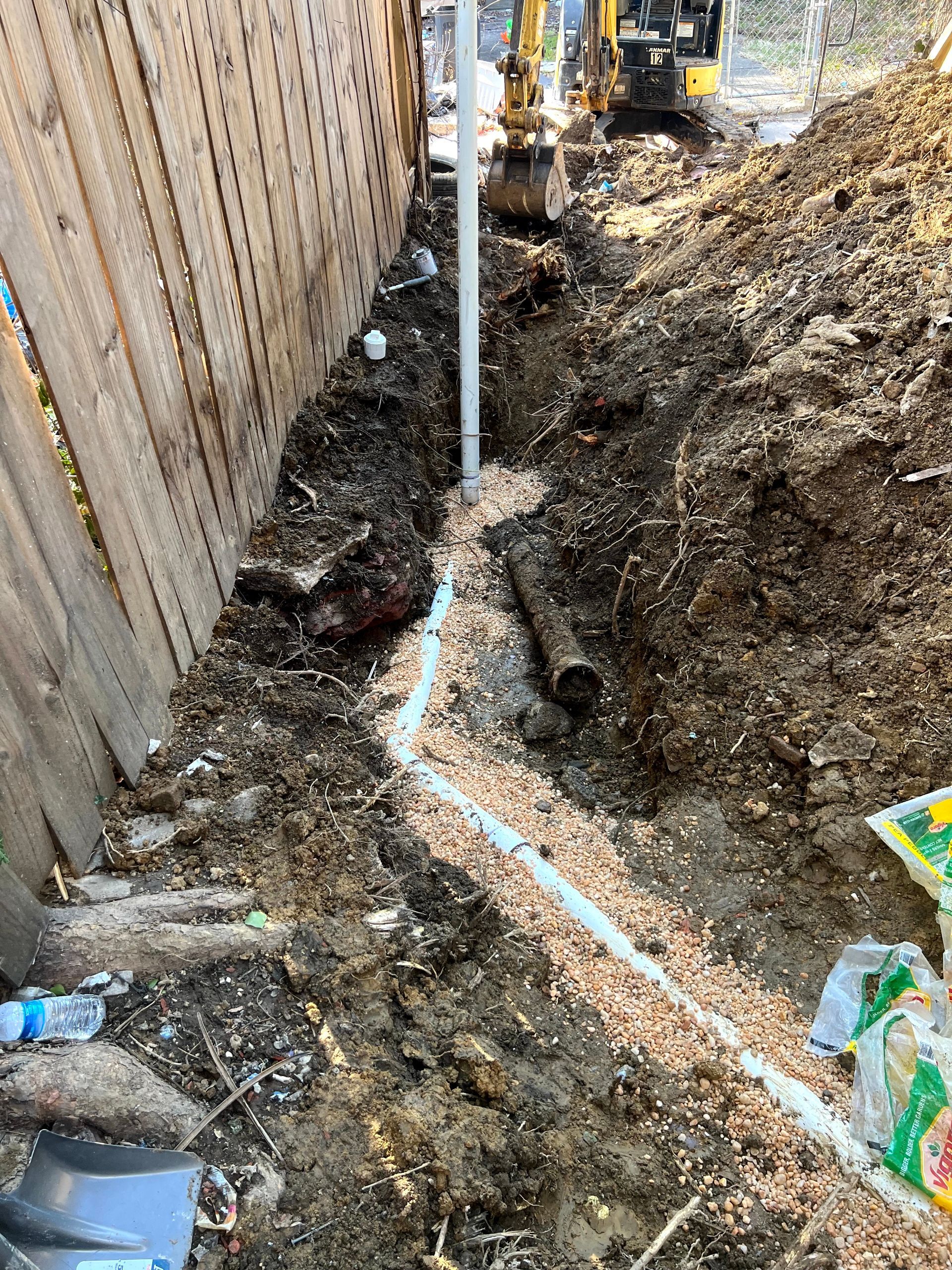 A man is digging a hole in the ground next to a fence.