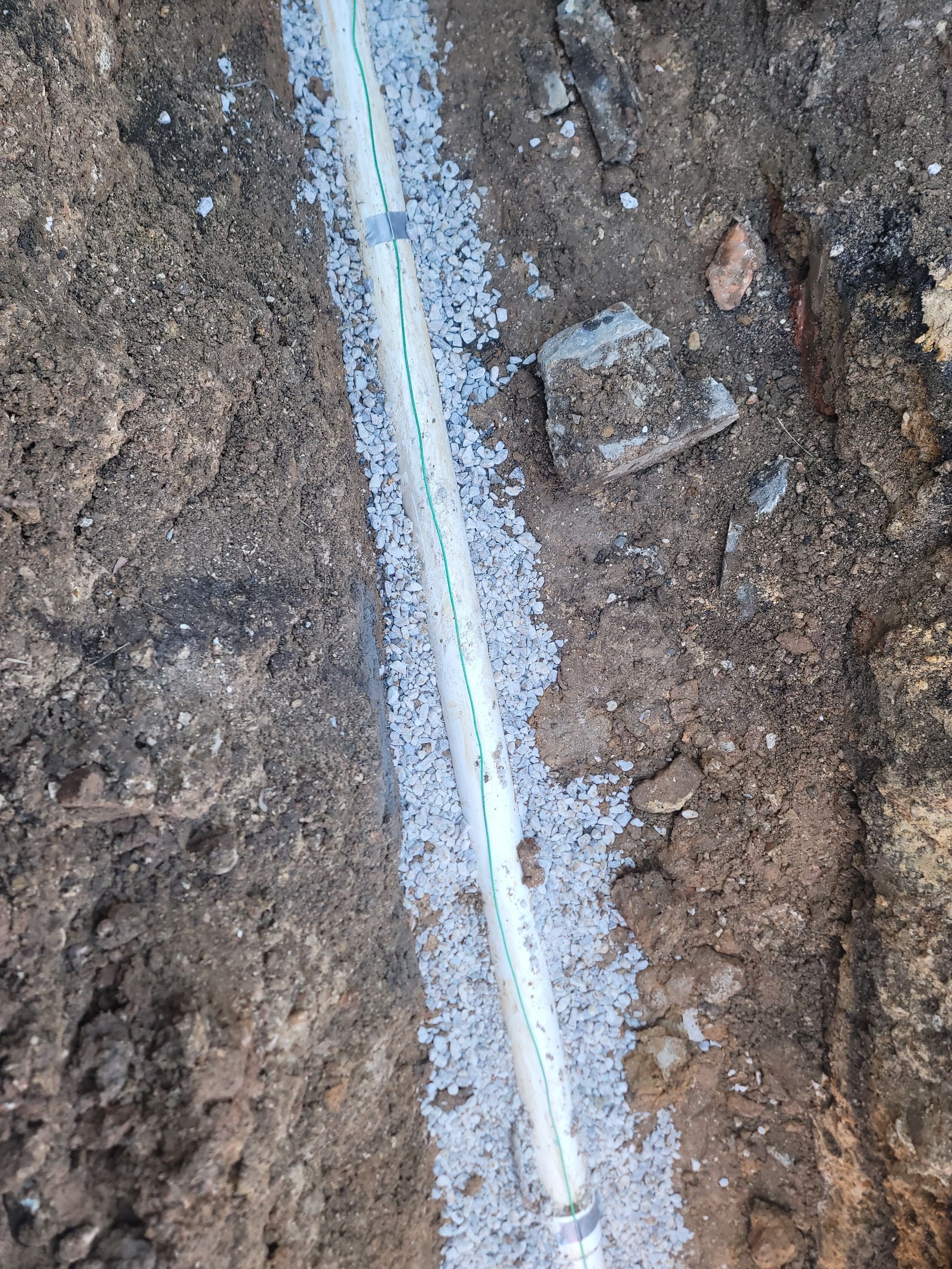 A white pipe is laying in the dirt.