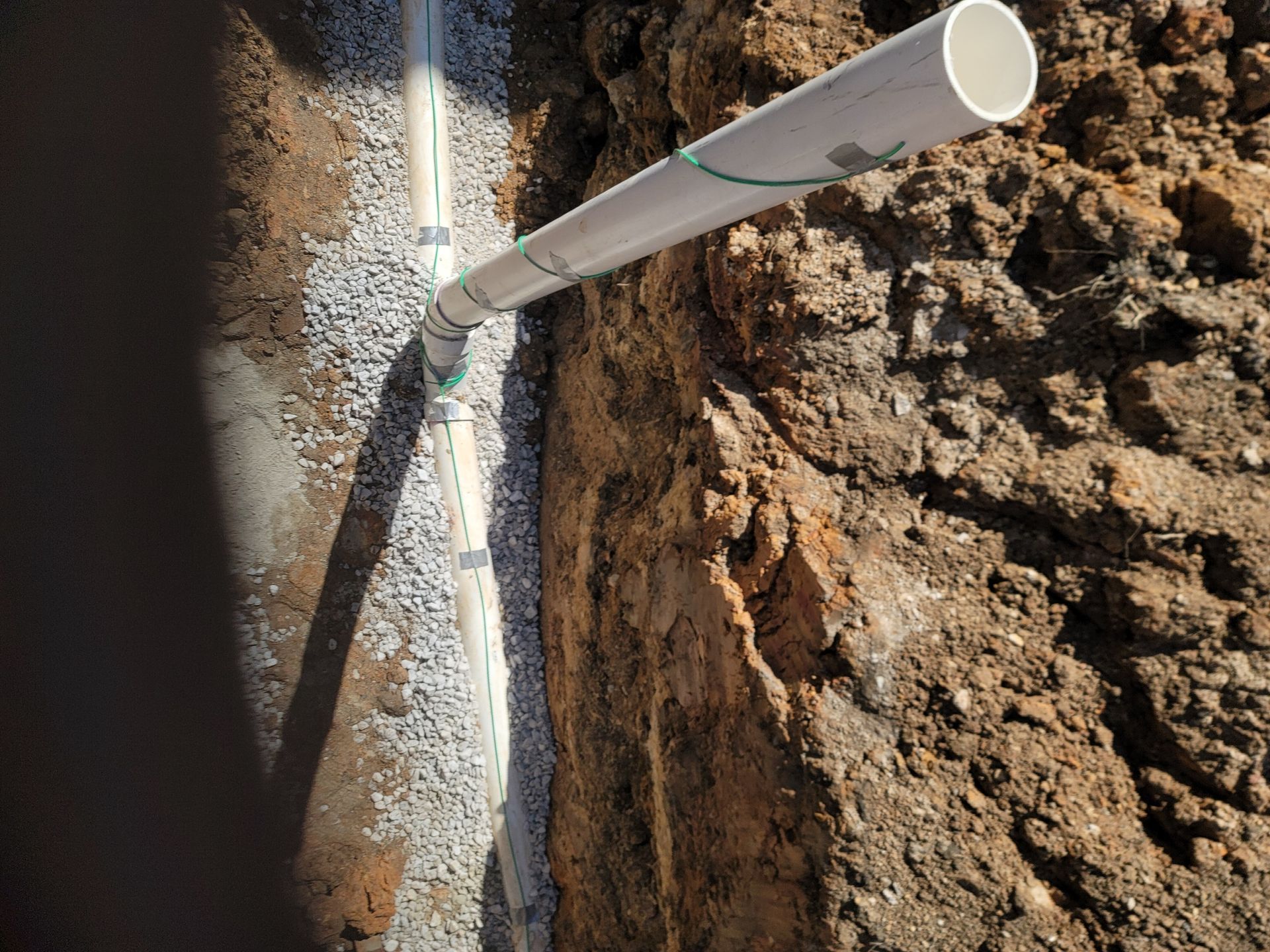 A white pipe is sticking out of a hole in the ground.