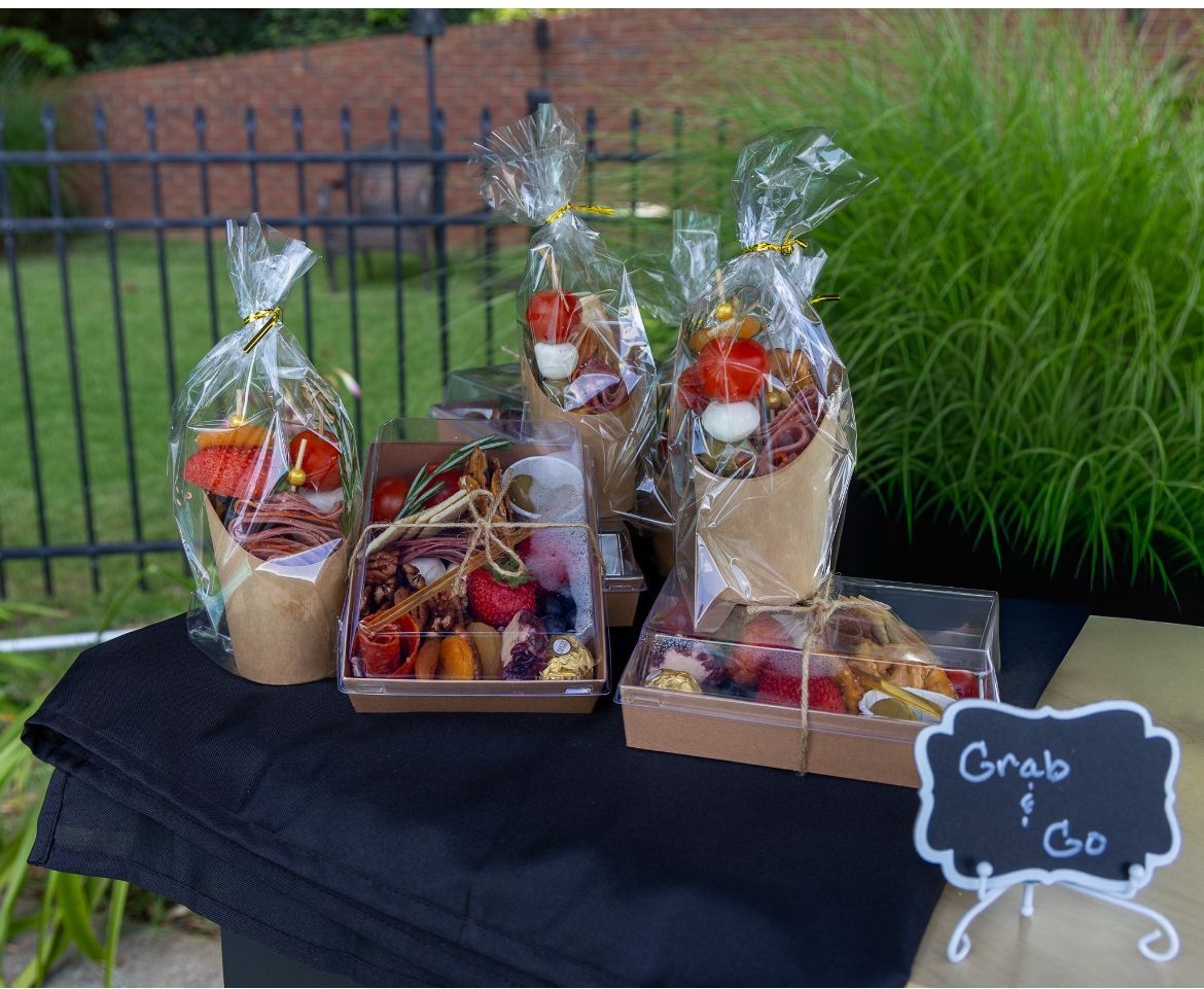 Gift basket with grapes, nuts, and a small jar of dip tied with a white ribbon