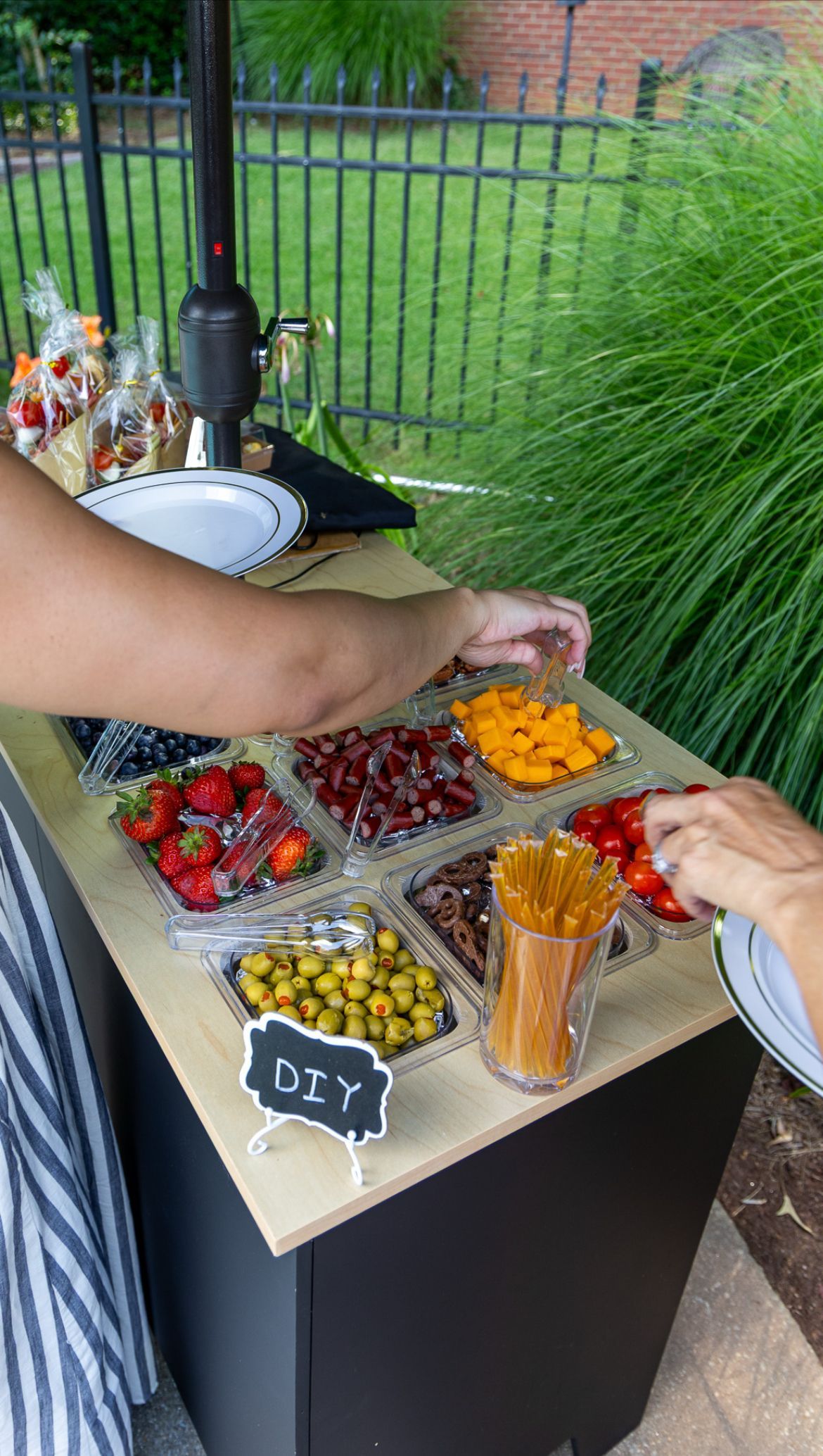 Tray of colorful mini dessert cones topped with green grapes and cream on a wooden display