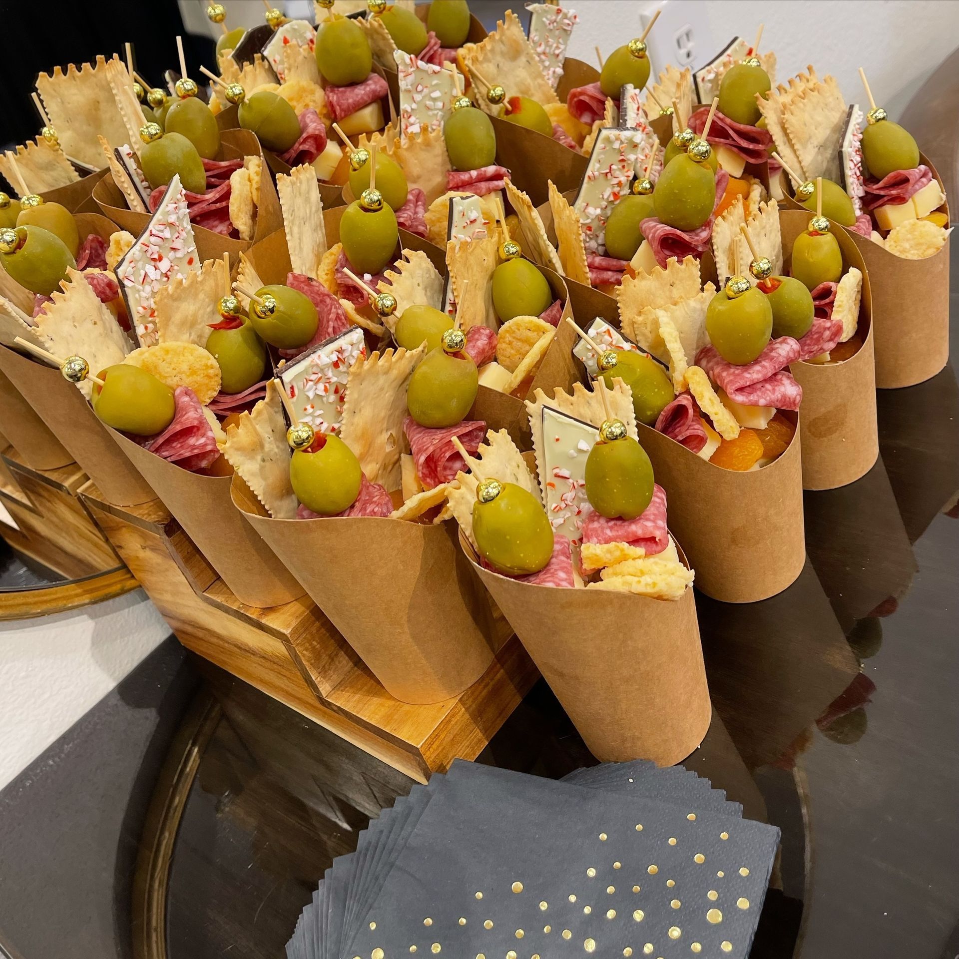 Tray of colorful mini dessert cones topped with green grapes and cream on a wooden display