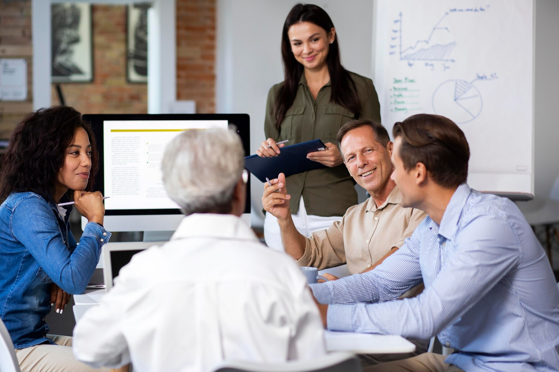A group of people are sitting around a table having a meeting.