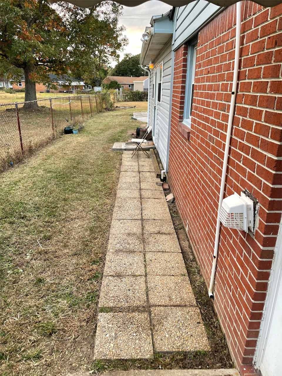 Brick house side with concrete walkway and yard.