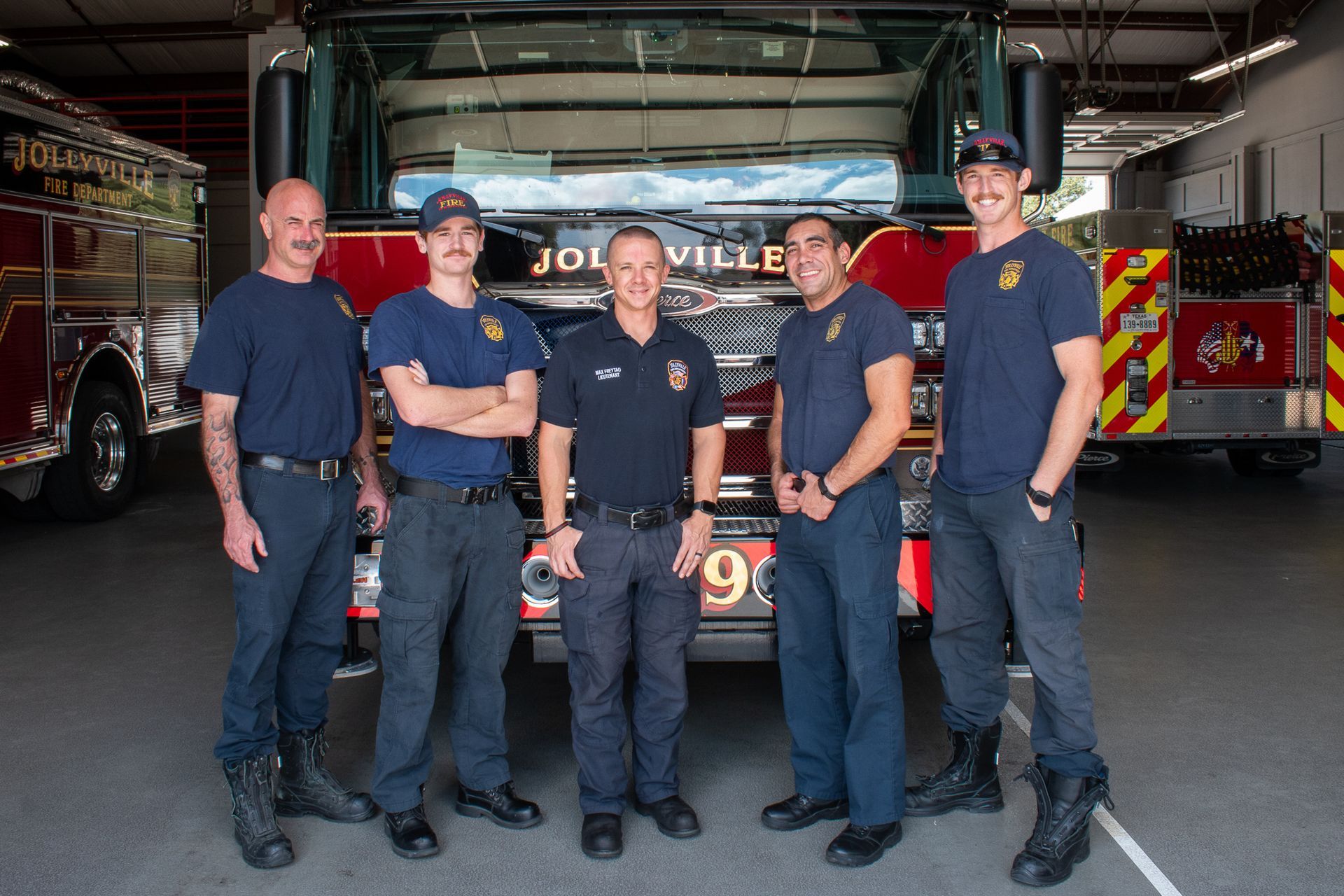 A group of firefighters are posing for a picture in front of a fire truck.