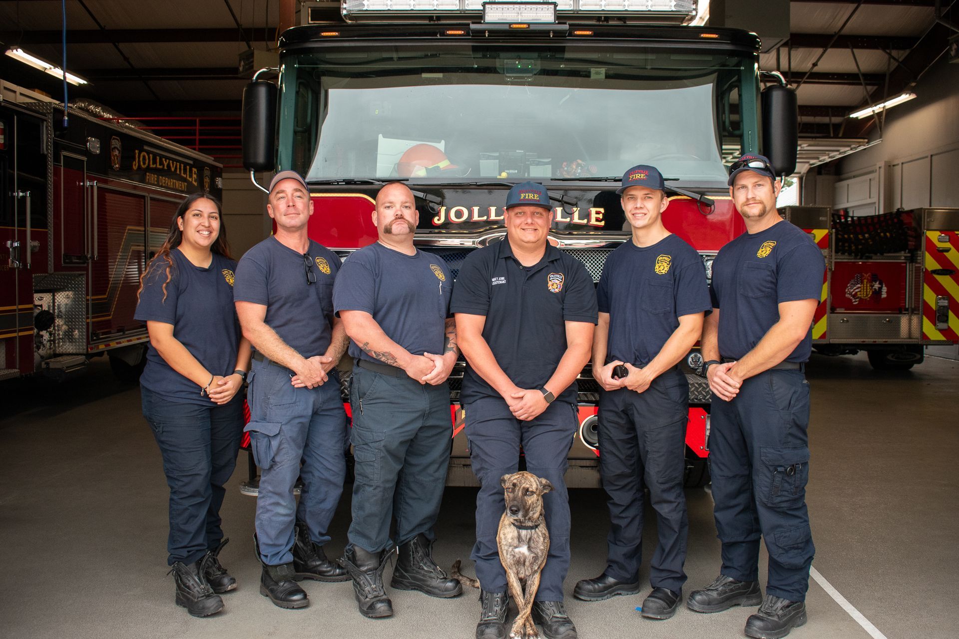 A group of firefighters are posing for a picture in front of a fire engine.