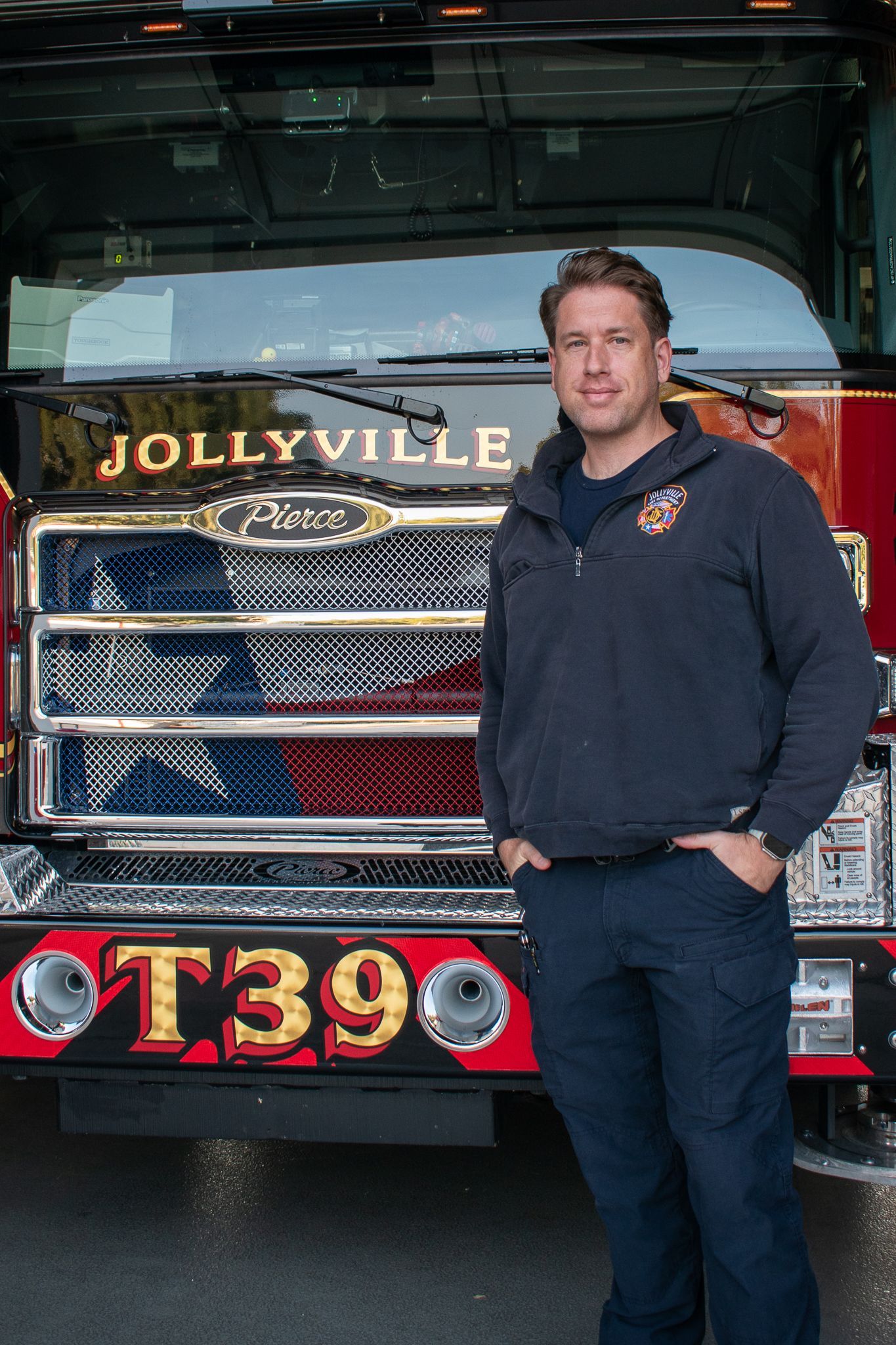 A firefighter is standing in front of a fire engine.