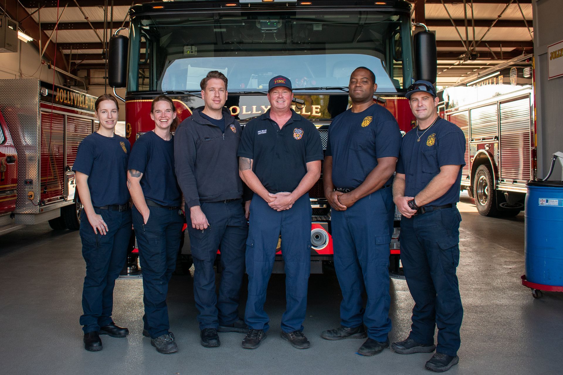 A group of firefighters are posing for a picture in front of a fire engine.