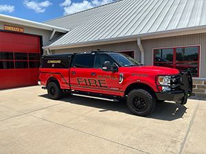 A red fire truck is parked in front of a fire station.