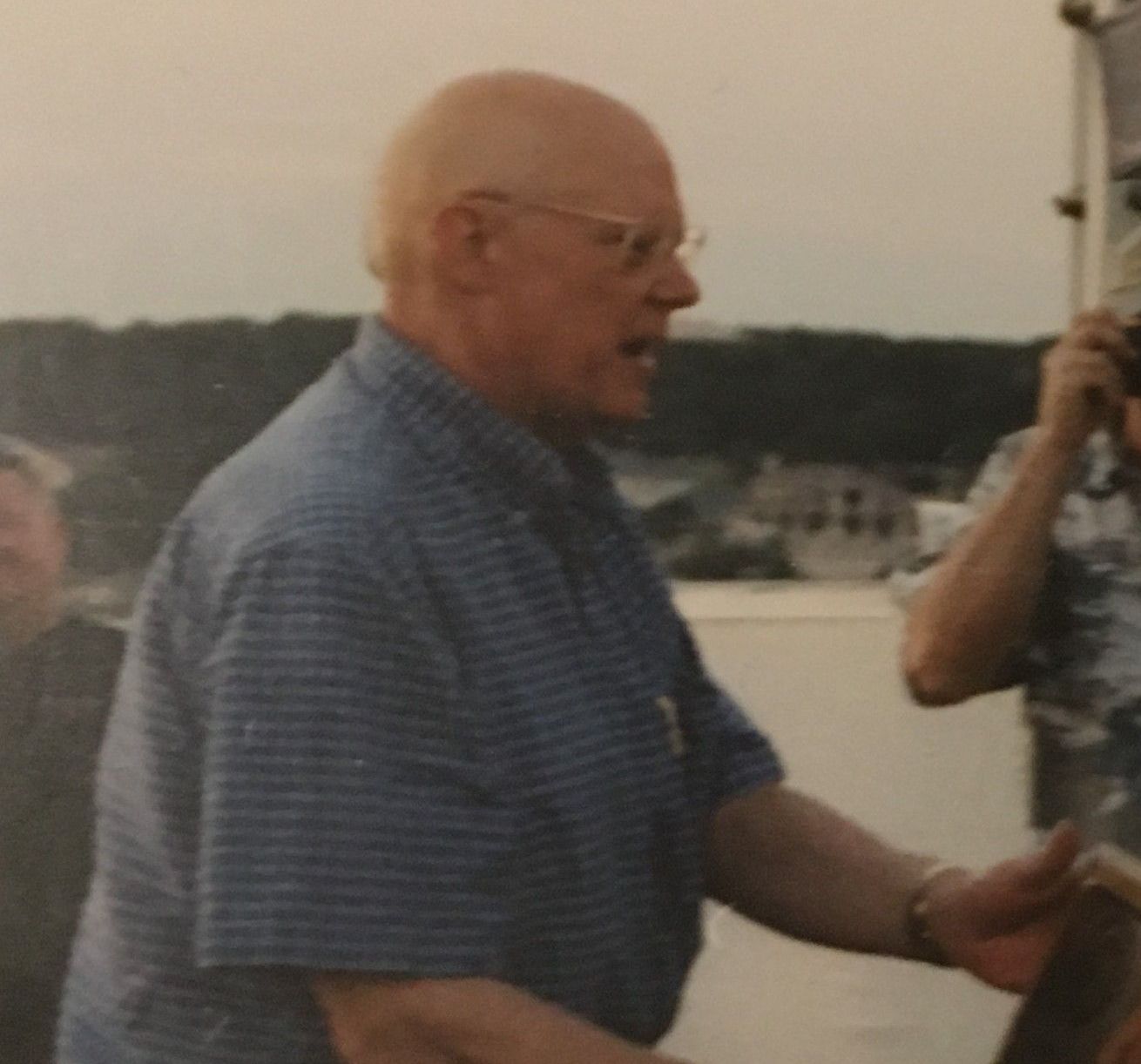 A man in a blue striped shirt is talking to another man