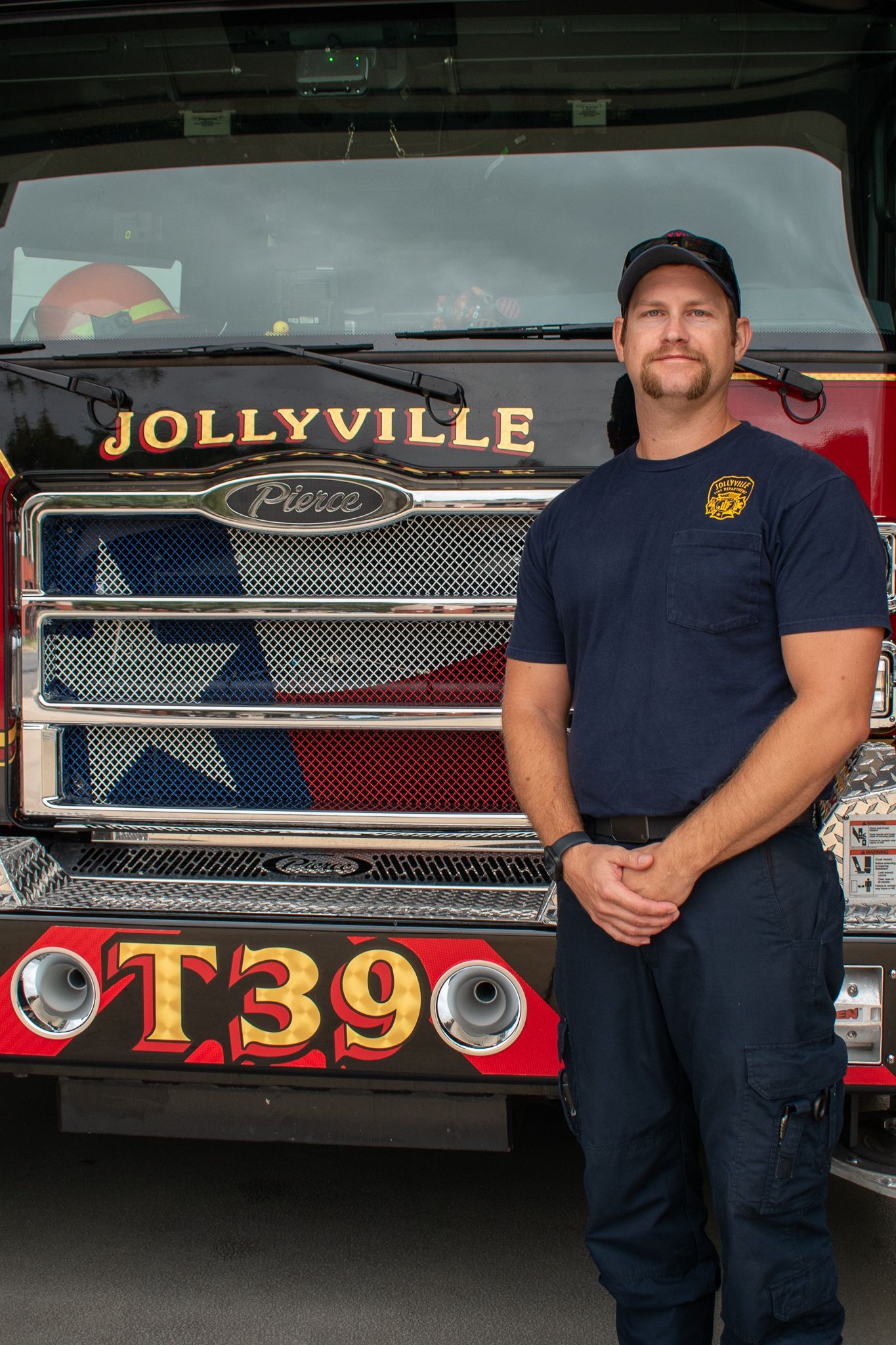 A firefighter  is standing in front of a fire engine.