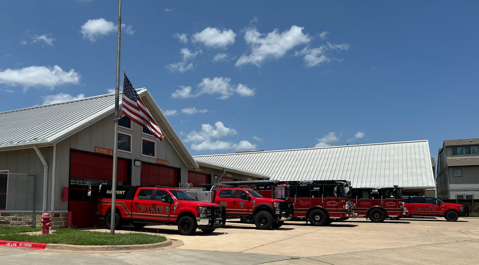 A row of fire trucks parked in front of a fire station.
