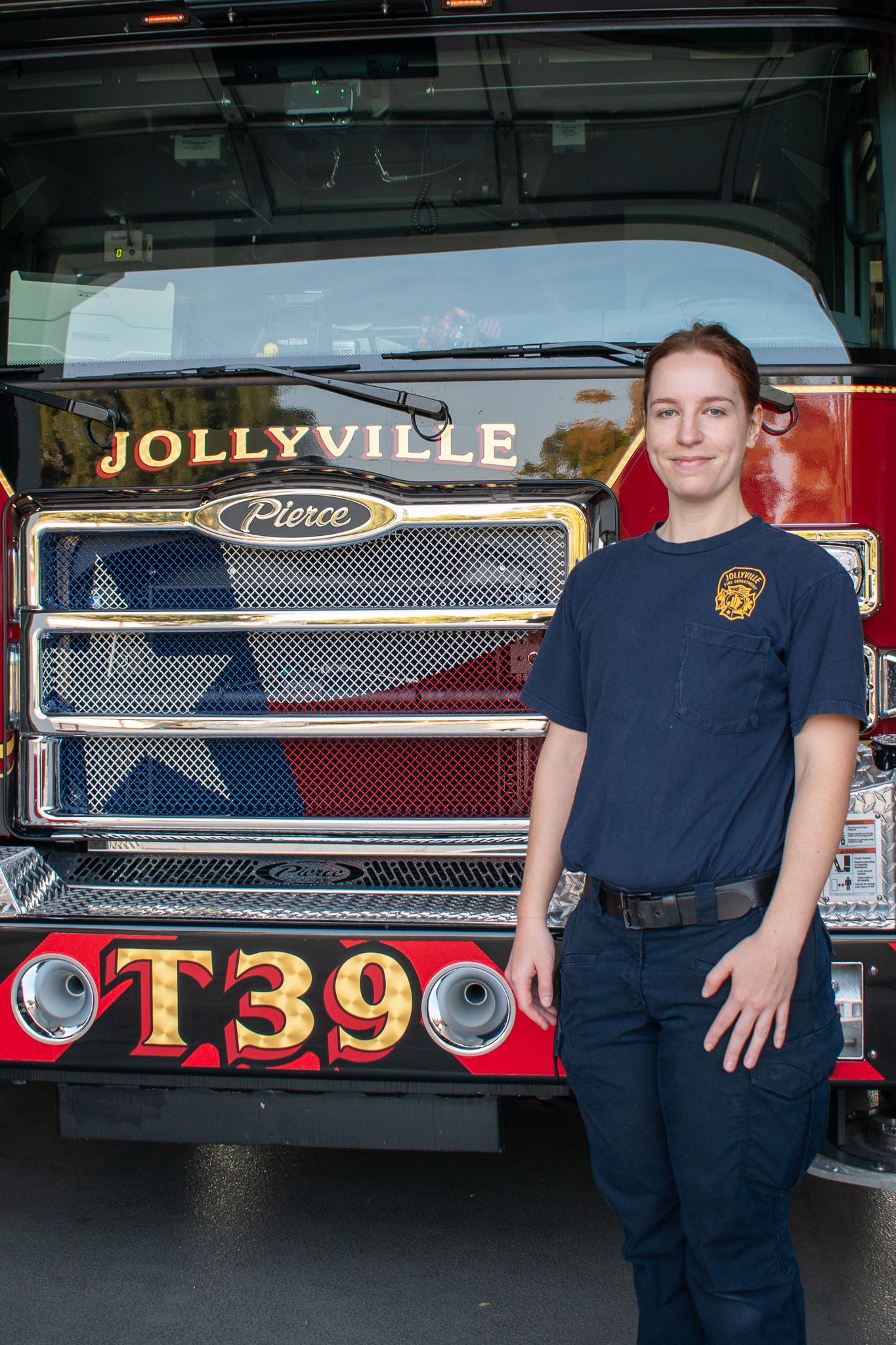 A firefighter  is standing in front of a fire engine.