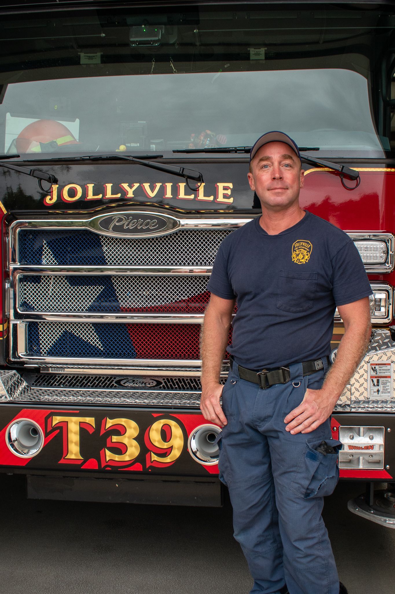A firefighter  is standing in front of a fire engine.
