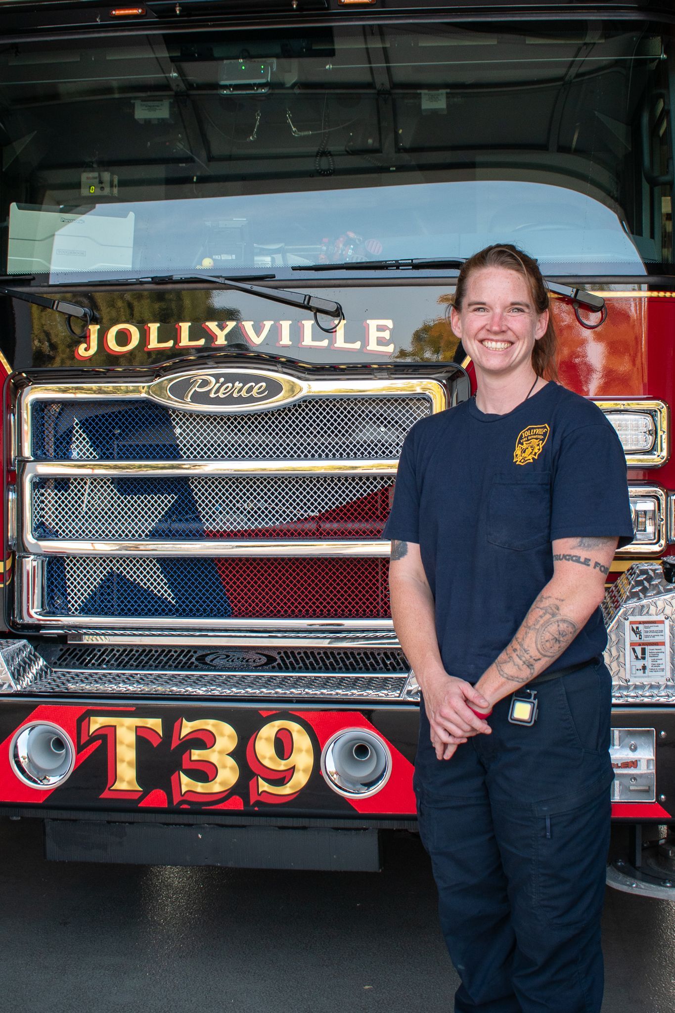 A firefighter  is standing in front of a fire engine.