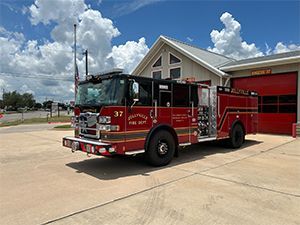 A red fire engine is parked in front of a fire station.