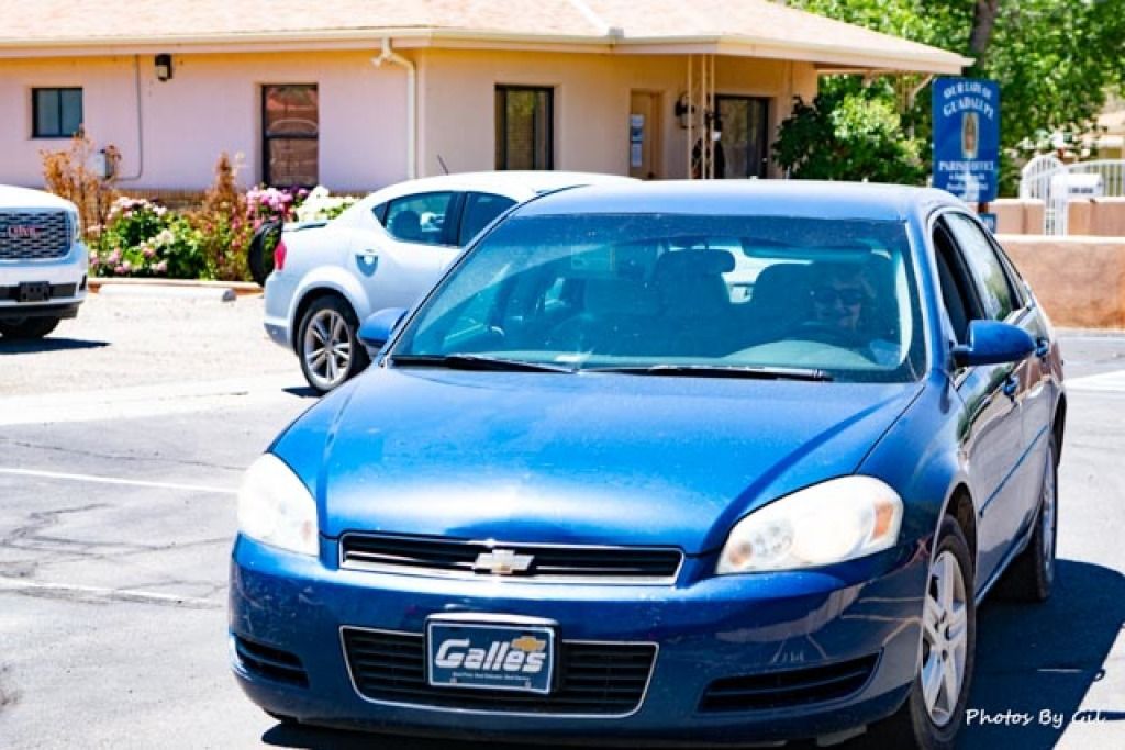 A blue Chevrolet sedan is parked in a sunny driveway.