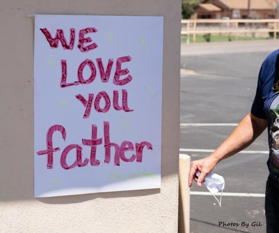 Poster taped to a wall reads We Love You Father in bold red letters. 