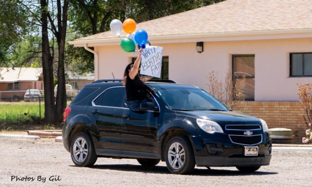 A person in a black SUV holds colorful balloons.