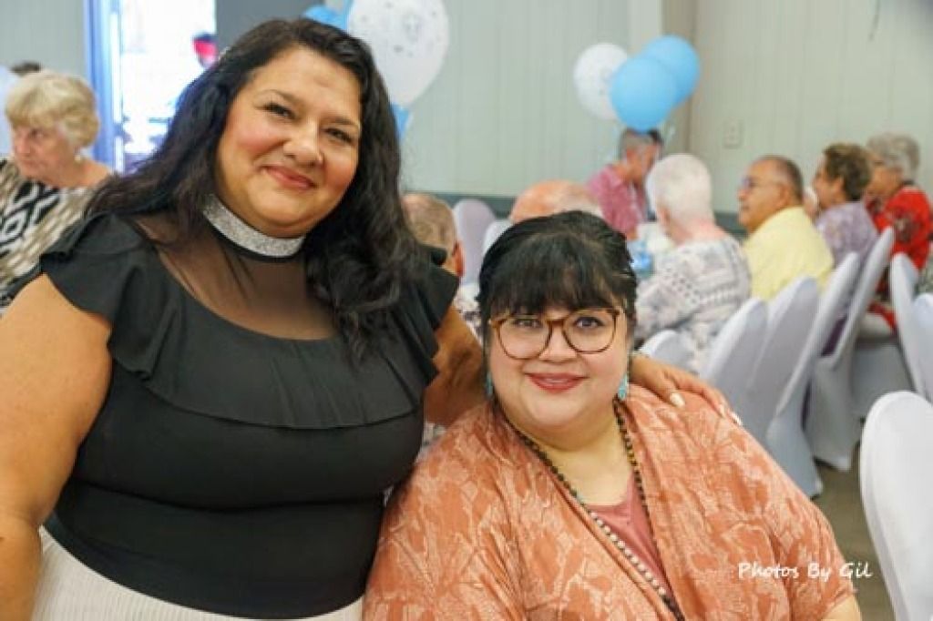 Two women smiling at a party. 