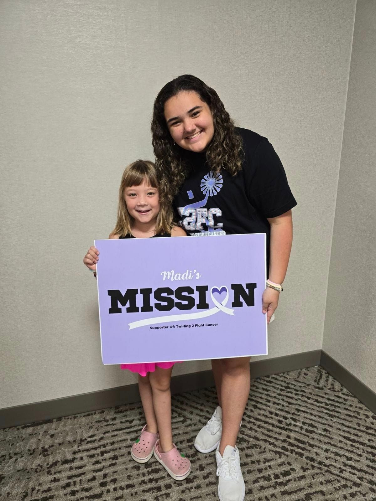A woman and a little girl are holding a sign that says mission.