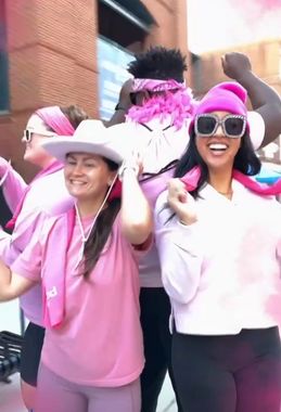 A group of people wearing pink shirts and hats are standing next to each other.