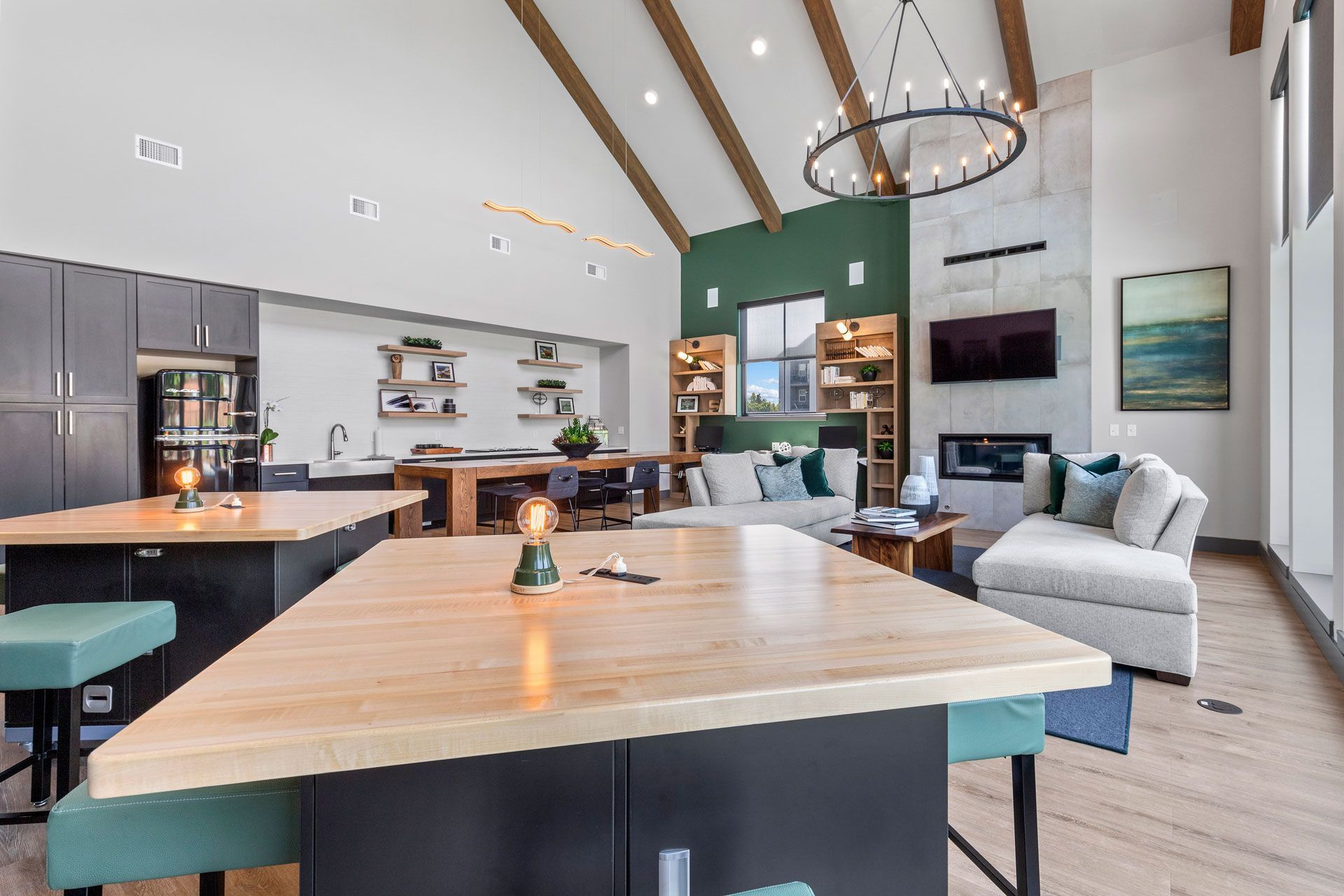 Modern apartment lounge with vaulted ceilings, exposed beams, kitchen islands, cozy sofas, and a fireplace.