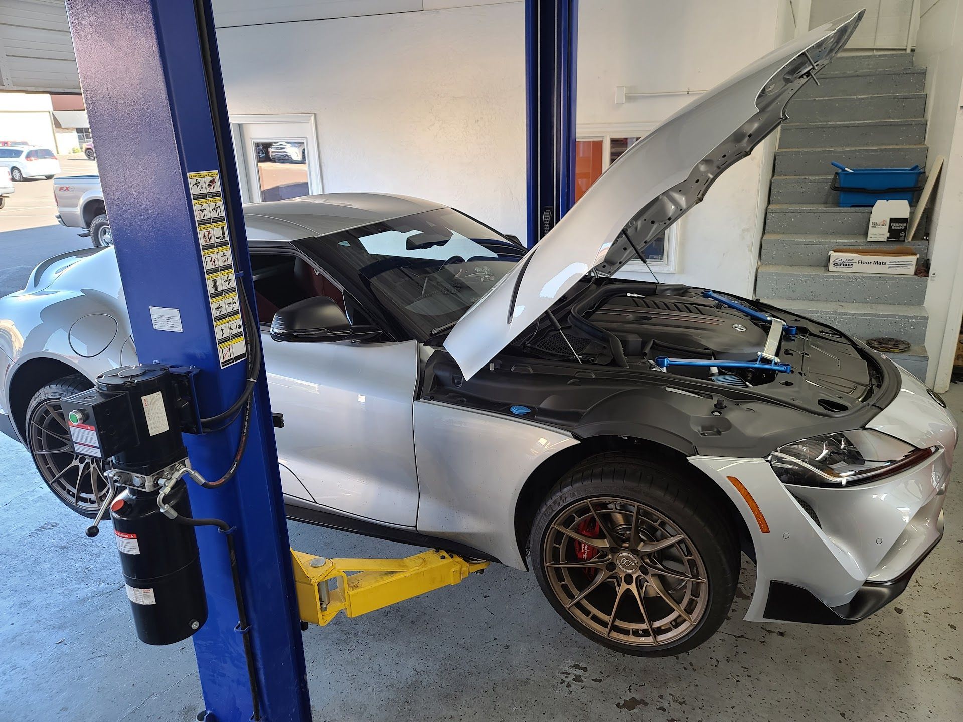 Silver Sports Car On Lift Undergoing Engine Service | Elston Auto Care