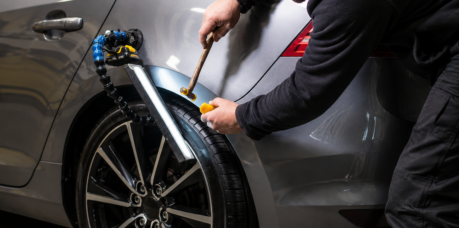 Person using a tire repair tool on a car wheel in a garage