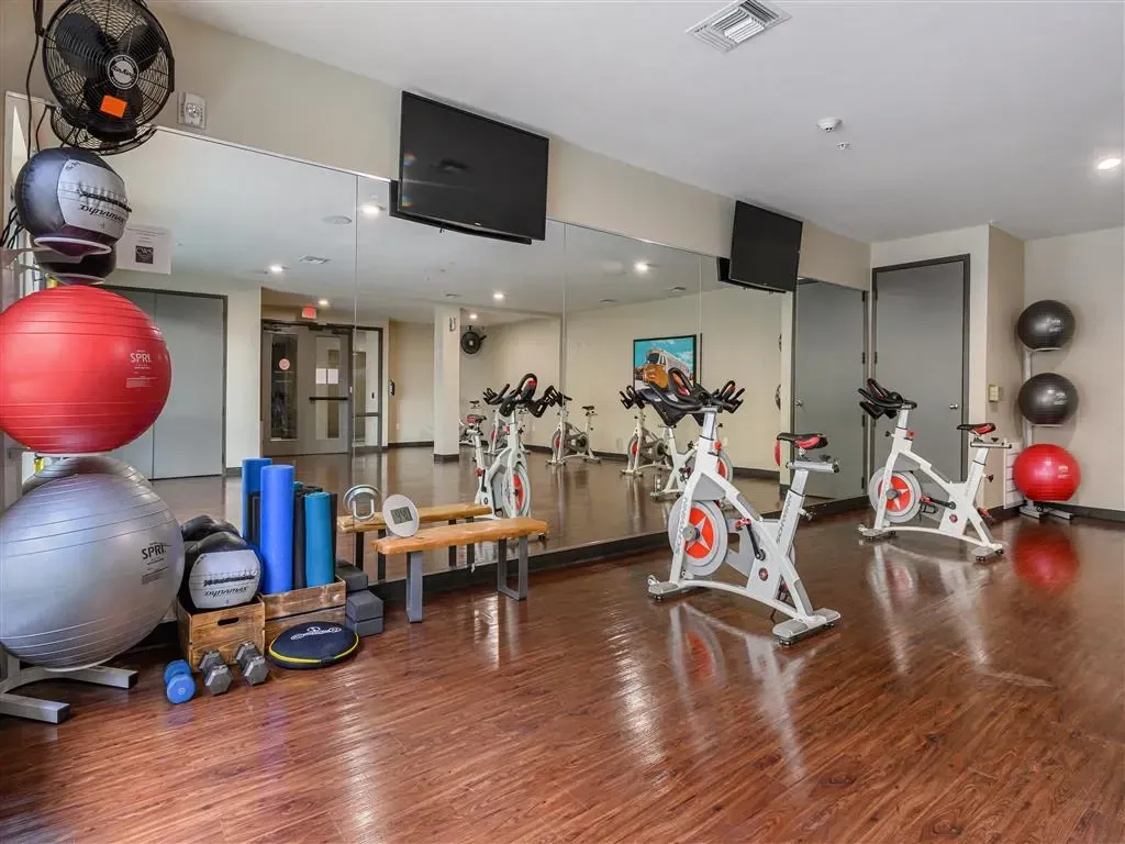 Fitness center with stationary bikes, exercise balls, weights, and mirrors.