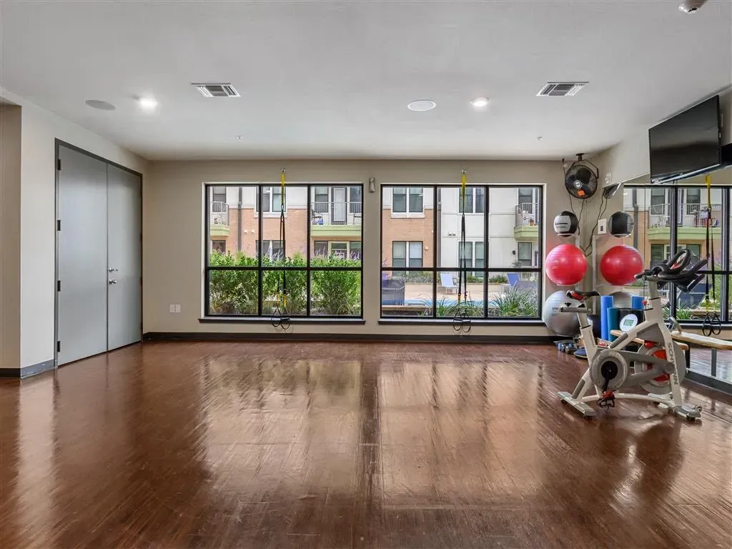 Interior view of a fitness center with exercise equipment and large windows overlooking the exterior.