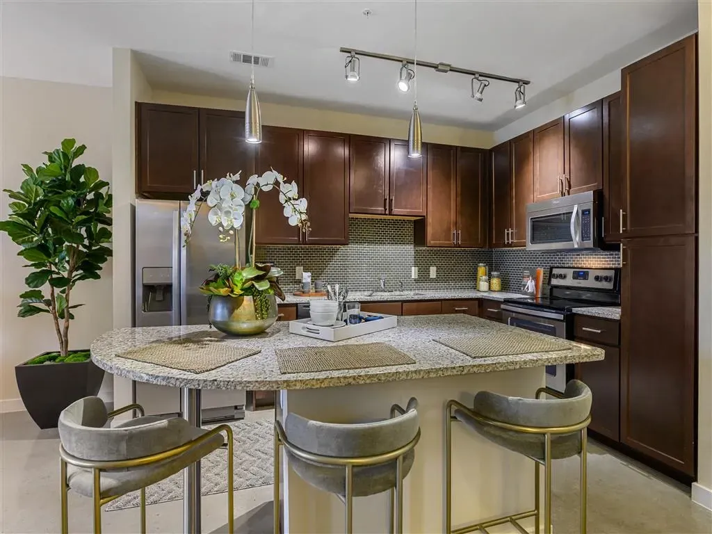 Modern kitchen with dark wood cabinets, granite countertops, stainless steel appliances, and a breakfast bar.