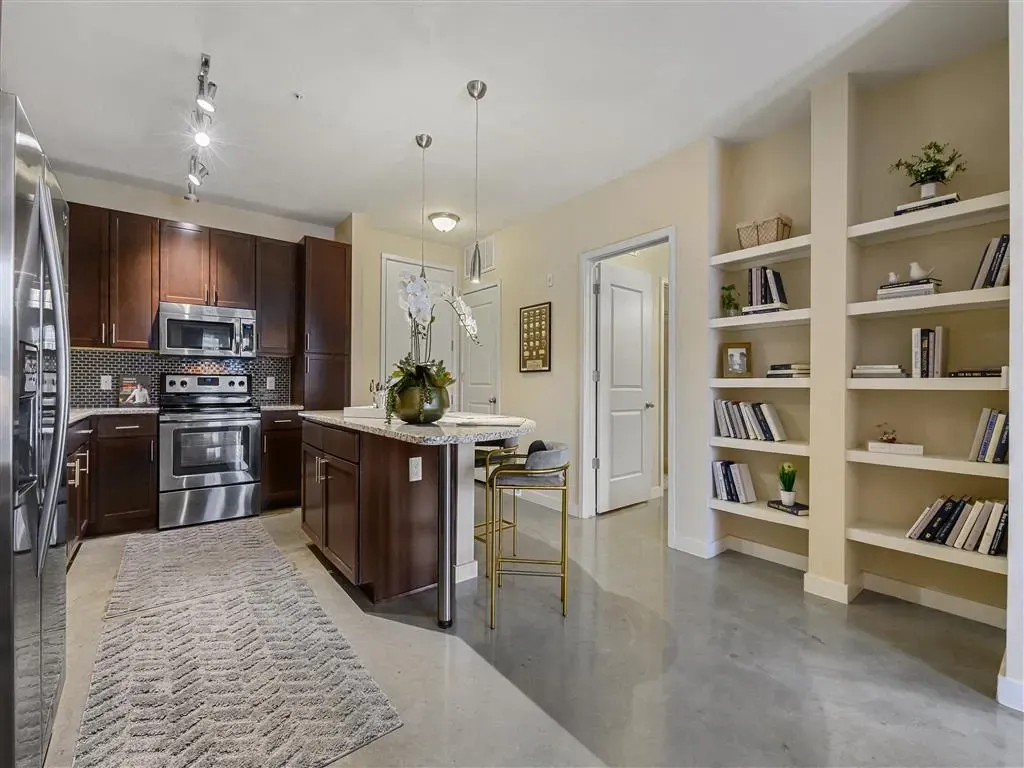 Modern kitchen with dark wood cabinets, stainless steel appliances, and a granite-topped island with bar stools.