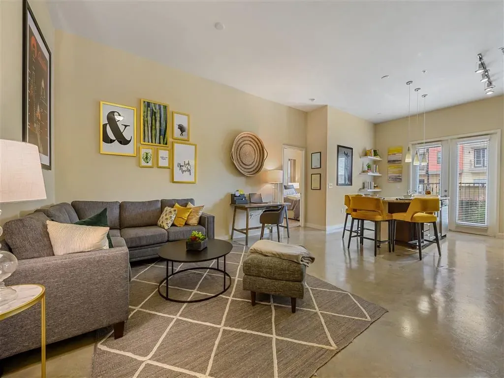 Modern living room and kitchen area with gray sectional sofa, coffee table, and bar seating.