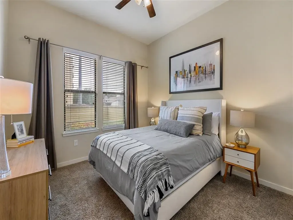 Bedroom with a queen-size bed, nightstand, dresser, and a ceiling fan.