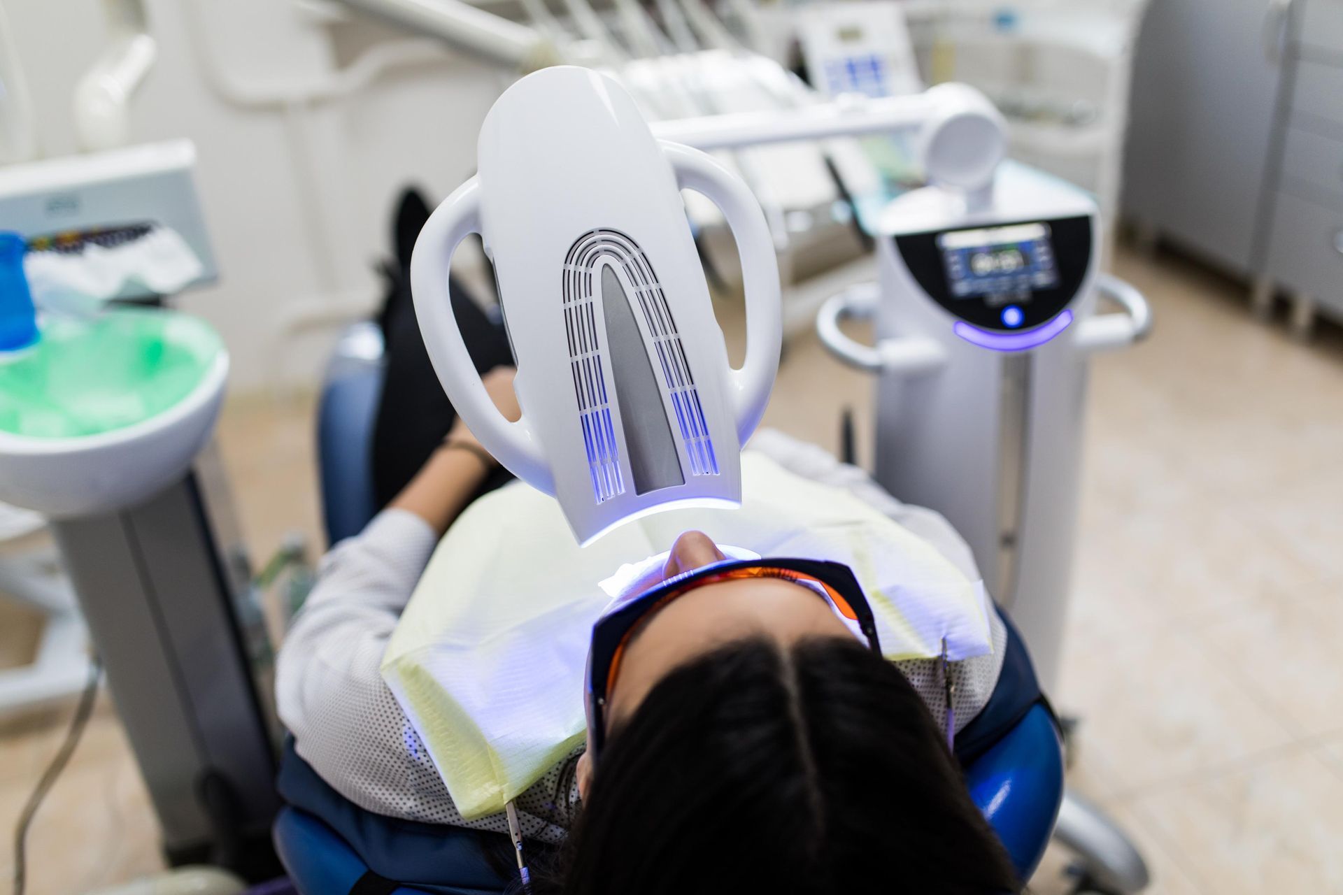 A woman is getting her teeth whitened in a dental office.