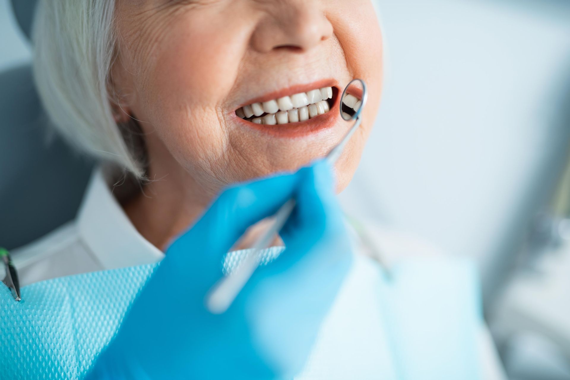 An elderly woman is having her teeth examined by a dentist.