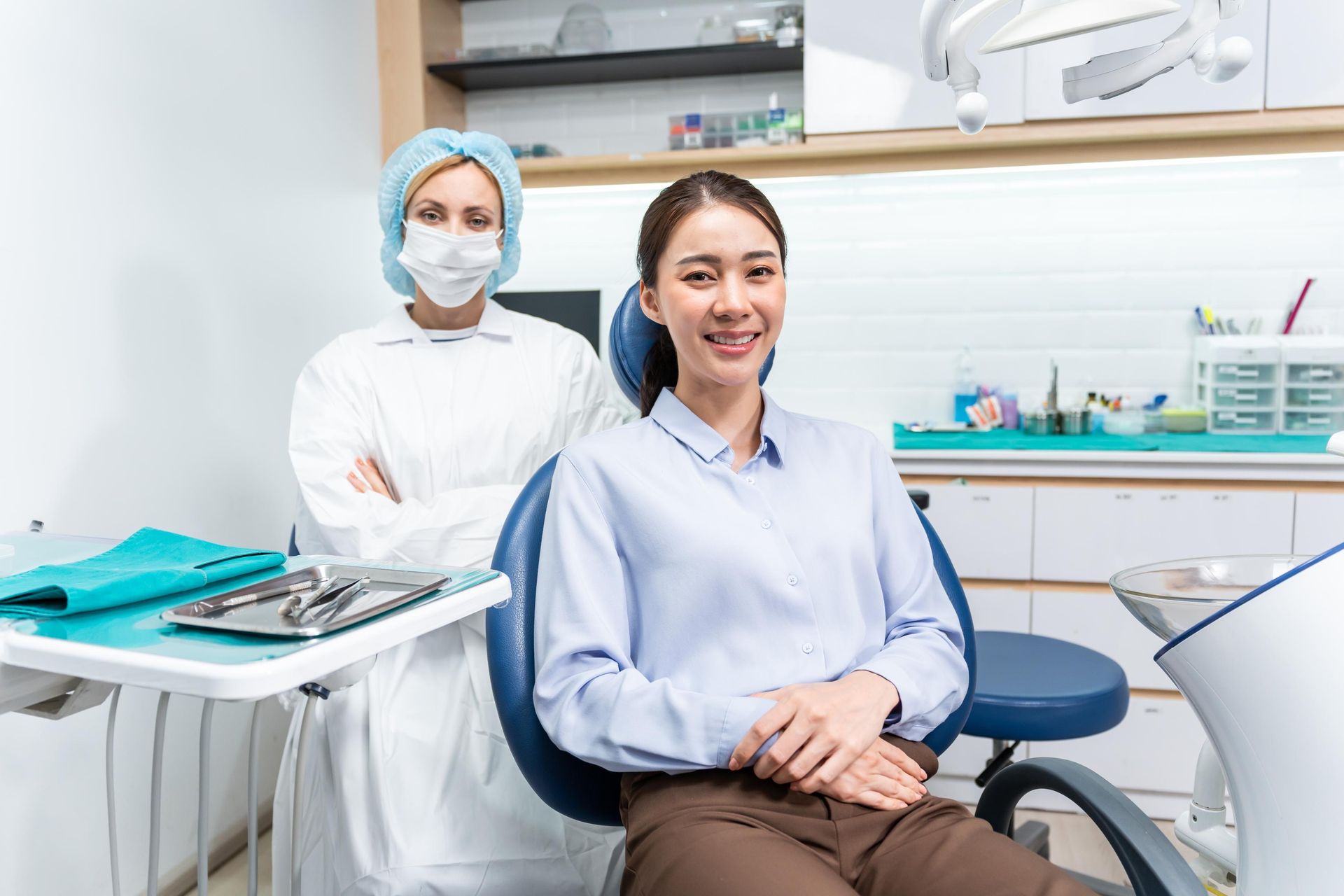 A woman is sitting in a dental chair next to a dentist.