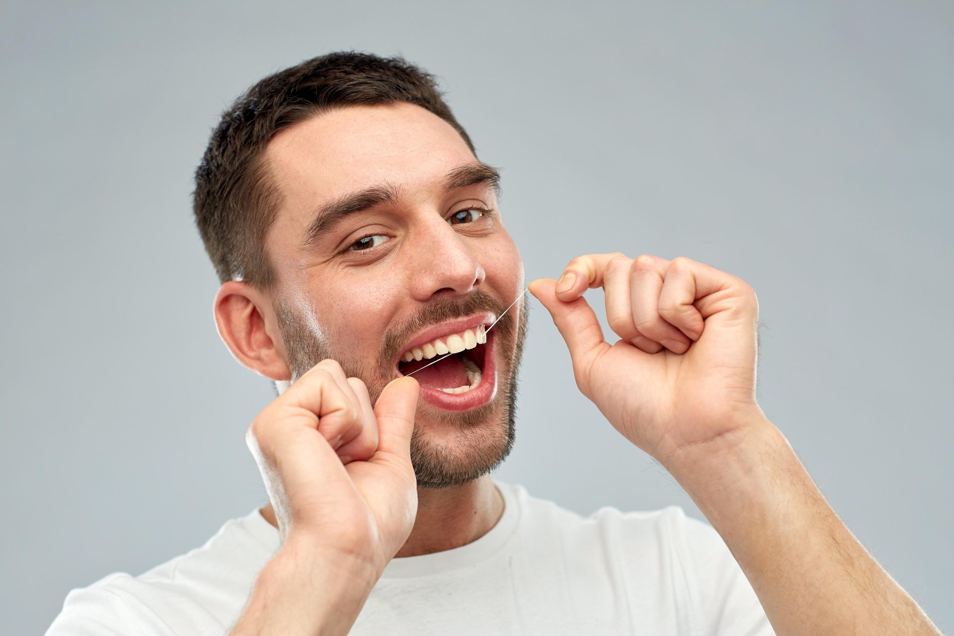 A man is flossing his teeth with a dental floss.