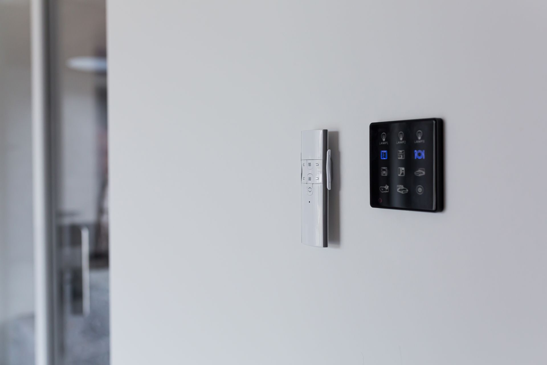 Wall-mounted smart home thermostat and light switch on a white wall