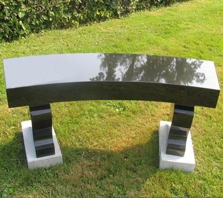 Black granite bench on a grassy lawn.