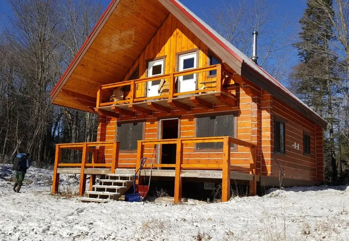 Outside view of Norm's Cabin, a 1.5 story cabin with peaked roof.
