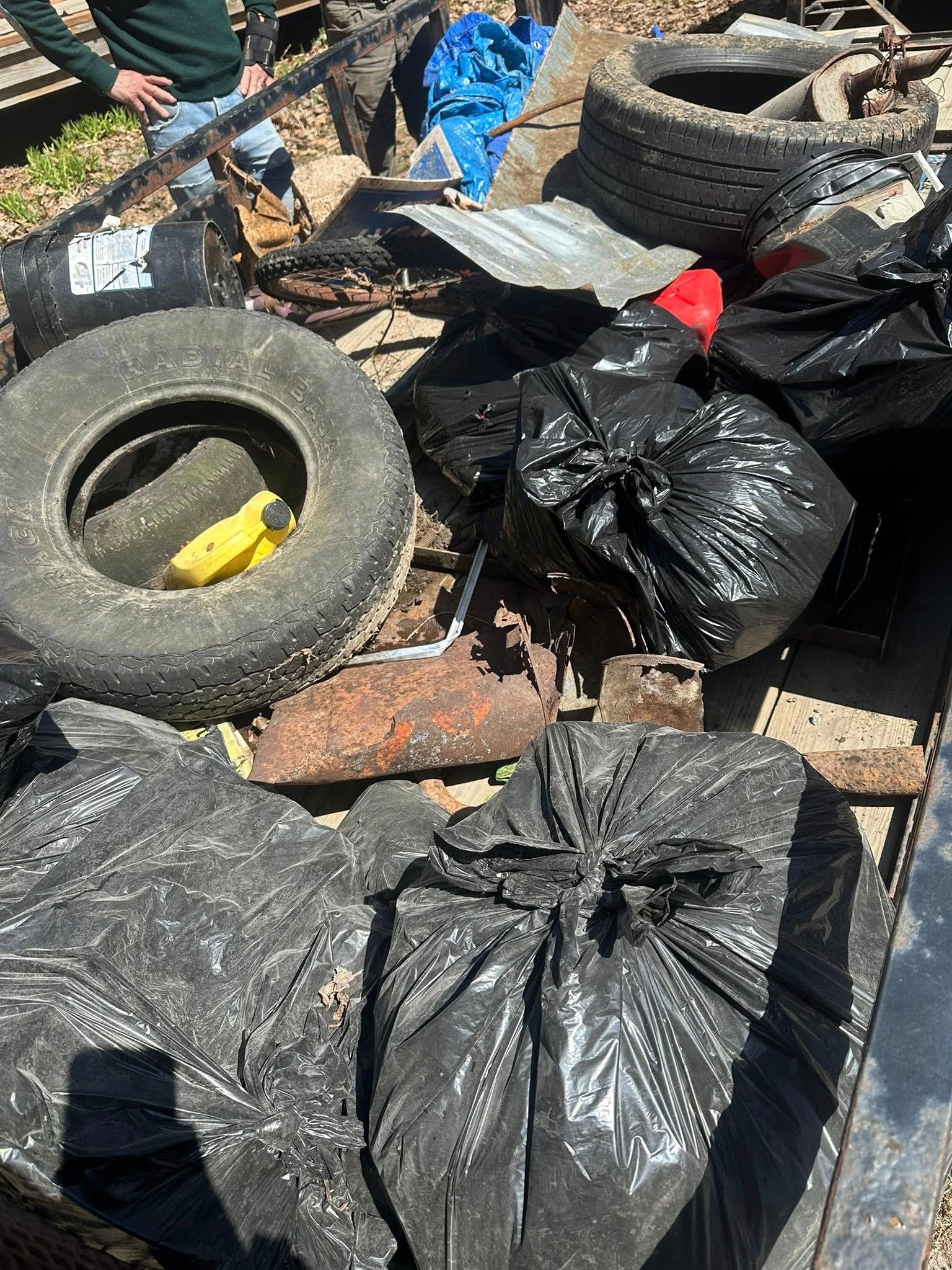 Tires, garbage bags, and debris collected, possibly a cleanup effort, outdoors.