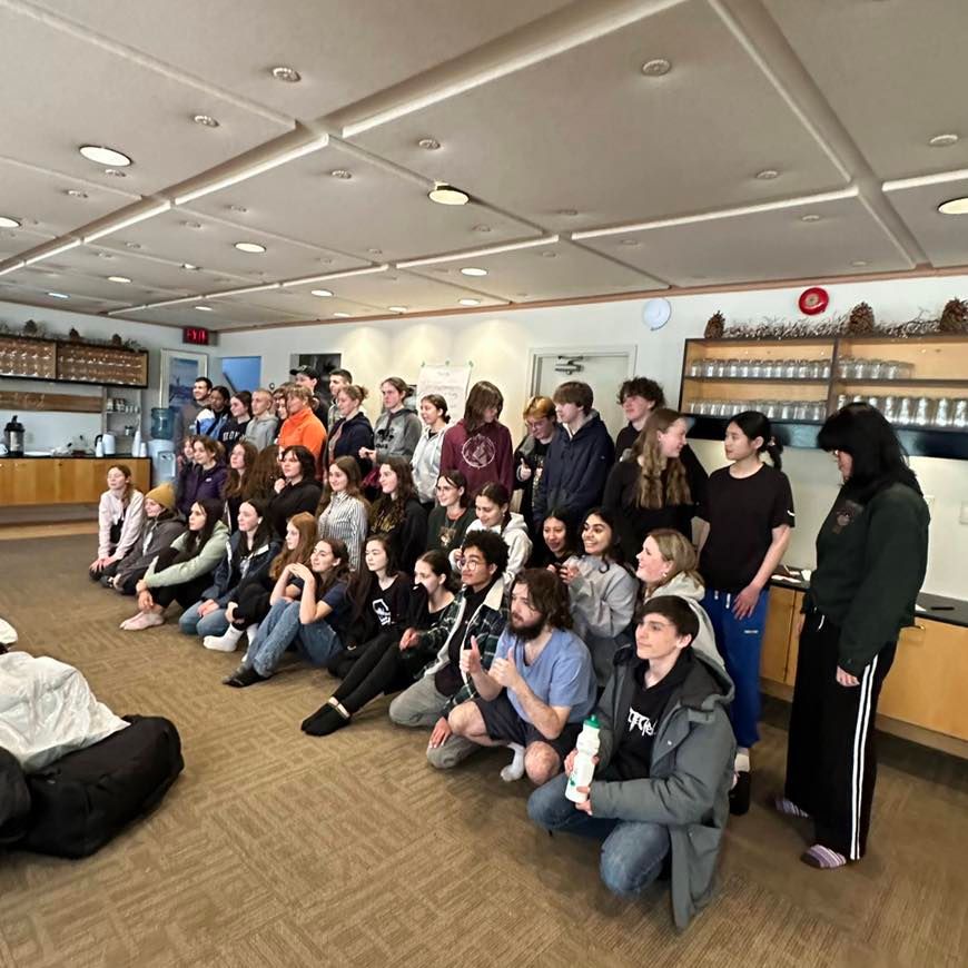 Group of students poses in a room with a low ceiling and neutral colors.