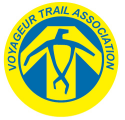 Voyageur Trail Association logo: Yellow circle with blue text, a blue and yellow geometric design.