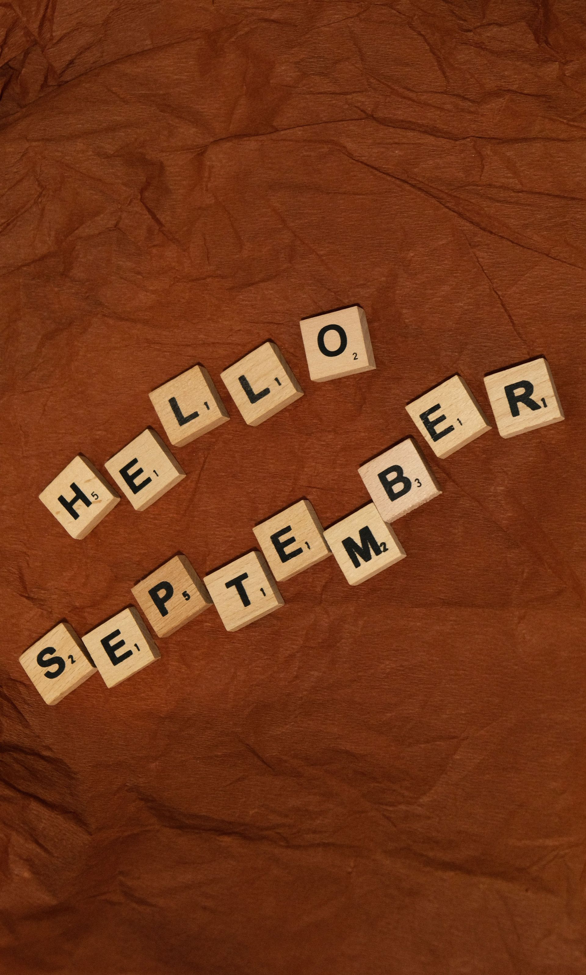 Letter tiles spelling “HELLO, SEPTEMBER” on a warm brown background.