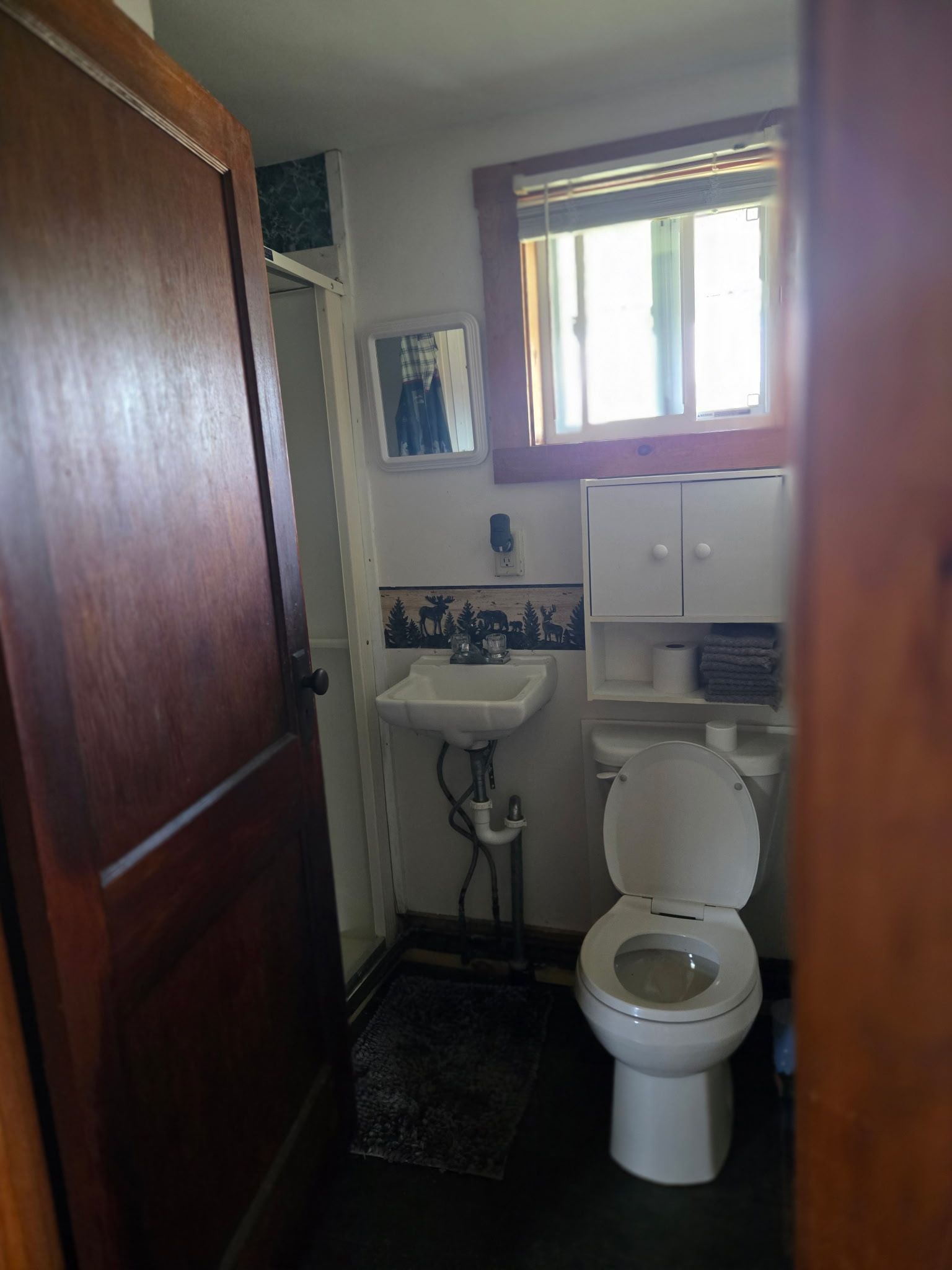 Small bathroom with toilet, sink, wall cabinet, and a window above the toilet.