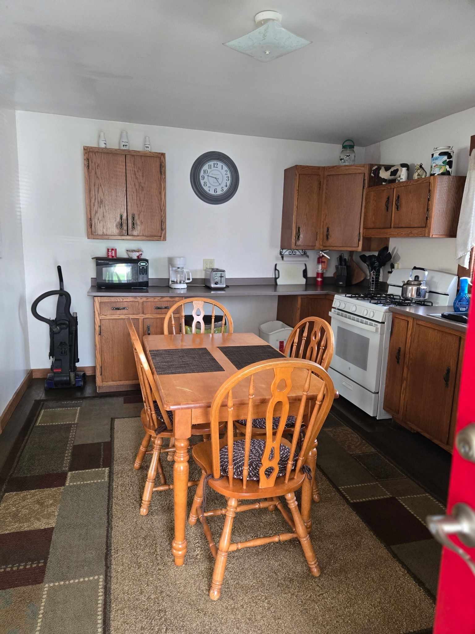 Cozy kitchen with wooden dining table and chairs, white appliances, and dark countertops.