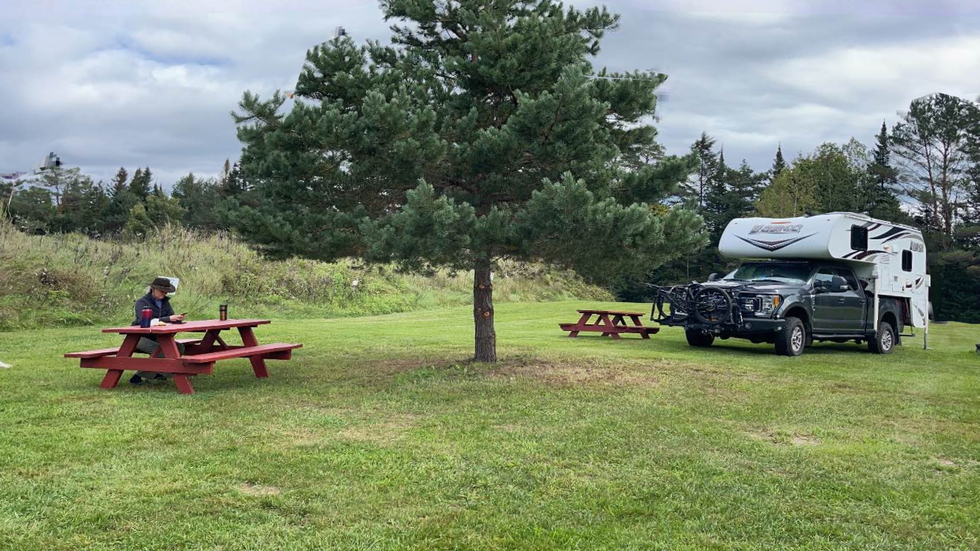 Clean campsite with firepit and picnic table surrounded by Vermont pines