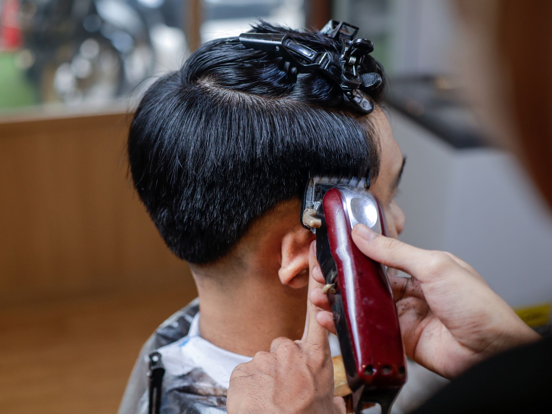Hairdresser clipping a short black haircut with electric clippers in a salon